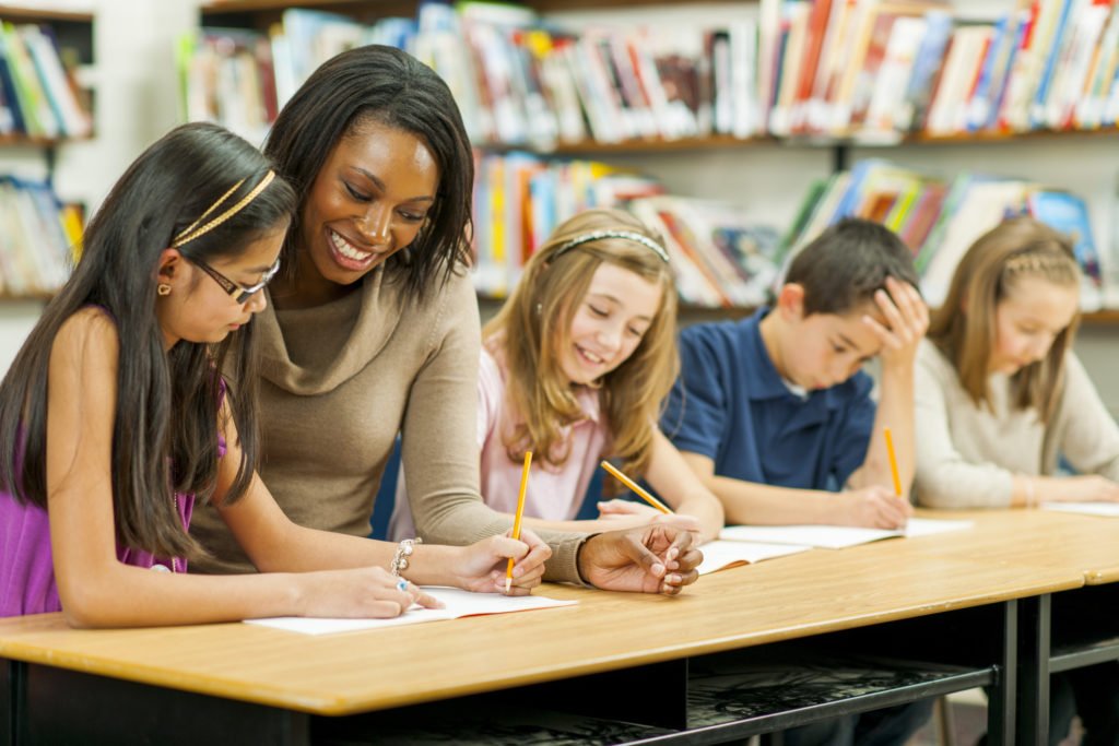 Teacher helping students in classroom - Classwork.com