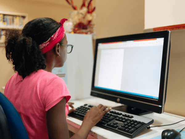 A child studying a worksheet on a desktop computer.