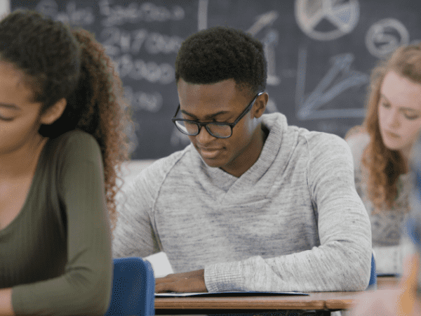 Three young students quietly studying at their desks.